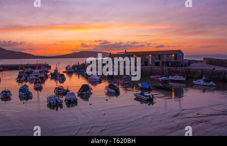 Lyme Regis, Dorset, Großbritannien. 28. April 2019. UK Wetter: Glorious sunrise im Cobb in Lyme Regis. Der Himmel glüht mit leuchtenden Farben im Cobb Hafen am Sonntag Morgen. Credit: Celia McMahon/Alamy leben Nachrichten Stockfoto