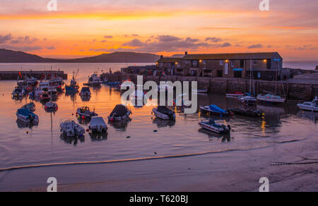 Lyme Regis, Dorset, Großbritannien. 28. April 2019. UK Wetter: Glorious sunrise im Cobb in Lyme Regis. Der Himmel glüht mit leuchtenden Farben im Cobb Hafen am Sonntag Morgen. Credit: Celia McMahon/Alamy leben Nachrichten Stockfoto