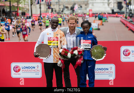 London, Großbritannien. 28 Apr, 2019. Der britische Prinz Harry (C) wirft mit Sieger der Männer von 2019 London Marathon, Kenias Eliud Kipchoge (L) und für Frauen Sieger Kenias Brigid Kosgei nach dem 2019 London Marathon, in London, UK, 28. April 2019. Credit: Richard Washbrooke/Xinhua/Alamy leben Nachrichten Stockfoto