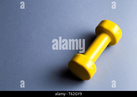 Eine gelbe Hantel liegen auf der blauen Tabelle, kopieren Raum. top View Photo, sportliches Leben, Gesundheit, Körperpflege Stockfoto