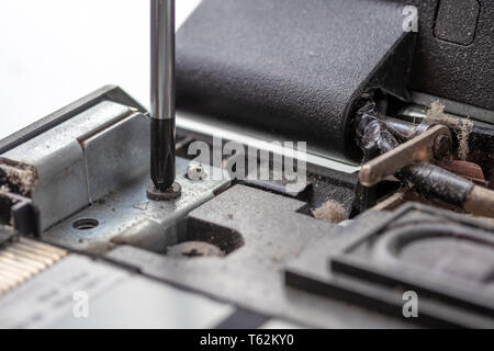 Den Schraubendreher schraubt die Befestigungsschraube des alten staubigen Prozessor Computer Board. Demontage Elektronik Reparatur und Reinigung. Teil der Laptop Stockfoto