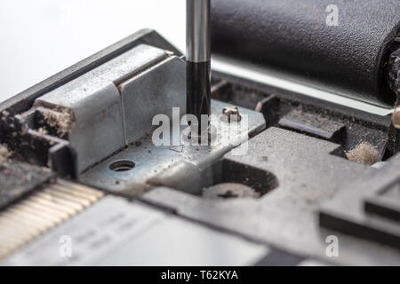 Den Schraubendreher schraubt die Befestigungsschraube des alten staubigen Prozessor Computer Board. Demontage Elektronik Reparatur und Reinigung. Teil der Laptop Stockfoto