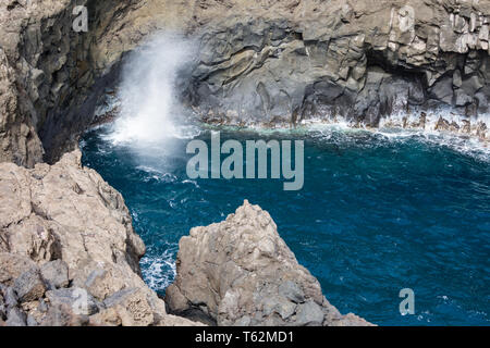 Eine Welle Spritzen gegen vulkanischen Felsen an der Küste von Los Cancajos auf La Palma, Spanien. Stockfoto