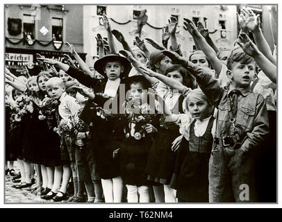 Österreichische Kinder Heil Hitler SALUTE 1930 Die NS-Propaganda Bild der Österreichischen Kinder Gruppe begrüßte Adolf Hitler mit traditionellen Heil Hitler salute mit erhobenen Armen. Swastika Symbol an der Wand im Hintergrund Sudetenland Stockfoto