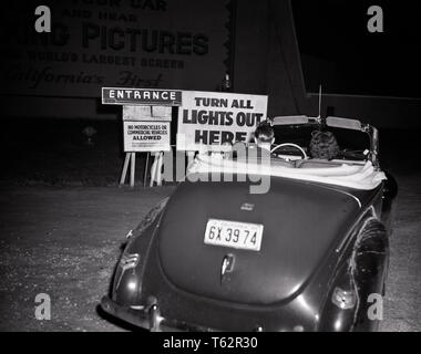 1940 s PAAR MANN FRAU IN CABRIO ZIEHEN IN DER DRIVE-IN-KINO EINGANGSSCHILD-asp ap 8925 ASP001 HARS TEENAGER UNTERHALTUNG B&W FILME DATING TRÄUME IN DER ATTRAKTION UMWERBUNG FLUCHT DATE NIGHT MOTION PICTURES MÖGLICHKEIT LAUFWERK IM DRIVE-IN NÄCHTLICHEN REARVIEW soziale Aktivität Miteinander junger erwachsener Mann JUNGEN ERWACHSENEN FRAU 1948 SCHWARZ UND WEISS KAUKASISCHEN ETHNIE UMWERBEN ALTMODISCH Stockfoto