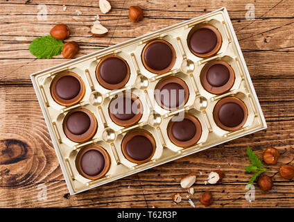 Box von hausgemachten Süßigkeiten auf hölzernen Hintergrund mit minzeblatt und Muttern. Eine Haselnuss in Caramel und Schokolade. Stockfoto