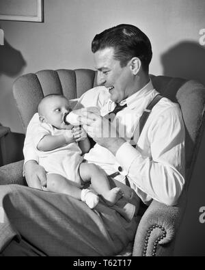 1940er Jahre 1950er Jahre Mann lächelnd vater SITZT IM WOHNZIMMER STUHL HALTEN UND MILCH Füttern mit der Flasche BABY BOY SOHN - b810DEB001 HARS ALTE ZEIT NOSTALGIE UMARMT ALTE MODE 1 FÜTTERUNG JUVENILE STYLE TEAMARBEIT KIND UMARMEN SÖHNE FREUEN FREUDE LIFESTYLE GESUNDHEIT LEBEN ZU HAUSE KOPIEREN RAUM MIT HALBER LÄNGE HUG PERSONEN PFLEGE MÄNNER, DIE VÄTER B&W AUGENKONTAKT GLÜCK FRÖHLICHE WOHNZIMMER UND VATIS STOLZ LÄCHELT HOSENTRÄGER VERBINDUNG FREUDIGE STILVOLLE DEB001 baby junge Jugendliche Mitte - Mitte - erwachsenen Mann ENTSPANNUNG ZWEISAMKEIT SCHWARZ UND WEISS KAUKASISCHEN ETHNIE ALTMODISCH Stockfoto