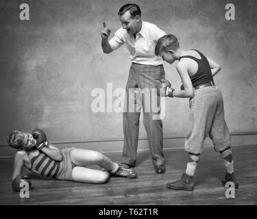 1930er Jahre zwei jungen SPARRING STANZEN VERPACKEN EIN junge KNOCKED DOWN MANN ALS SCHIEDSRICHTER ZÄHLEN IHN-b 8272 HAR 001 HARS ZUFRIEDENHEIT STUDIO SHOT GESUNDHEIT LEICHTATHLETIK KOPIE RAUM VOLLER LÄNGE KÖRPERLICHE FITNESS PERSONEN MÄNNER RISIKO ATHLETISCHE HANDELN B&W ABENTEUER SCHUTZ STÄRKE AUFREGUNG OUTFITS ERHOLUNG STOLZ STANZEN VERBINDUNG ATHLETEN ZUSAMMENARBEIT IHM JUGENDLICHE klopfte Mitte - Mitte - erwachsenen Mann SPAR SPARRING SCHWARZ UND WEISS KAUKASISCHEN ETHNIE HAR 001 ALTMODISCH Stockfoto