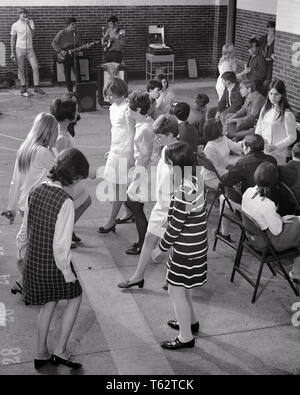 1950s 1960s GRUPPE VON JUGENDLICHEN MÄDCHEN TANZEN DER SPAZIERGANG AM SOCK HOP DANCE IN DER HIGH SCHOOL FITNESSRAUM mit LIVE BOY ROCK AND ROLL BAND-d 5741 HAR 001 HARS LIFESTYLE SOUND GESCHICHTE MUSIKER FEIER SOCKE KOPIE RAUM FREUNDSCHAFT IN VOLLER LÄNGE PERSONEN MÄNNER PUBERTIERENDE TEENAGER UNTERHALTUNG B&W GLÜCK HOHEN WINKEL LIVE ERHOLUNG AN IN DER Sporthalle an der HIGH SCHOOL MUSICAL INSTRUMENT HIGH SCHOOL VERBINDUNG STILVOLLE TEENAGED ROCK UND ROLL ZUSAMMENARBEIT GITARREN HOP JUGENDLICHE SOCK HOP SPAZIERGANG ZWEISAMKEIT SCHWARZ UND WEISS KAUKASISCHEN ETHNIE HAR 001 ALTMODISCH Stockfoto