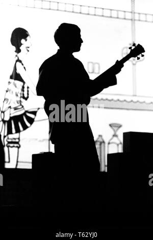 1970 s ANONYME SILHOUETTED TEENAGER MANN ELECTRIC BASS GUITAR PLAYER IM CLUB VENUE-m 8971 HAR 001 HARS MUSIKINSTRUMENT PHANTASIE STILVOLLE anonyme Kreativität junger erwachsener Mann SCHWARZ UND WEISS HAR 001 ALTMODISCH VERANSTALTUNGSORT Stockfoto