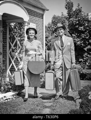 1940s 1950s PAAR MANN FRAU VERLASSEN HAUS MIT BLICK AUF DIE KAMERA ZU BEGINN EINER REISE GEPÄCK KOFFER UND HATBOX-s 985 HAR 001 HARS FREUDE LIFESTYLE FRAUEN HÄUSER VERHEIRATET EHEPARTNER EHEMÄNNER GESUNDHEIT LEBEN ZU HAUSE KOPIEREN RAUM FREUNDSCHAFT IN VOLLER LÄNGE DAMEN PERSONEN WOHN- MÄNNER GEBÄUDE VERTRAUEN B&W AUGENKONTAKT FREIZEIT Anzug und Krawatte GLÜCK FRÖHLICHEN ABENTEUER FREIZEIT REISE URLAUB RICHTUNG FERIEN WOHNUNGEN LÄCHELT FRÖHLICH RESIDENCE STILVOLLE HATBOX WEISSE HANDSCHUHE ZUSAMMENARBEIT HUT HÜTE Mitte - Mitte - erwachsenen Mann Mitte der erwachsenen Frau ZWEISAMKEIT FERIEN FRAUEN ANFANG SCHWARZ UND WEISS KAUKASISCHEN ETHNIE Stockfoto