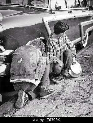 1950 zwei Jungen in zerlumpter Kleidung Diebstahl von Radkappen VON AUTO AUF DER STRASSE EIN KIND ALS LOOKOUT-w 1763 HAR 001 HARS AUTOMOBIL MÄNNER GEFAHR JUGENDJUNGEN SNEAKERS RÄUBER DENIM STEHLEN B&W DIEB RAUB ABENTEUER AUTO EINBRUCH VERBINDUNG KOMBI AUTOMOBILE TEENAGED FAHRZEUGE KAPITALVERBRECHEN ILLEGALEN JUGENDLICHEN PRE-TEEN PRE-TEEN BOY ZWEISAMKEIT SCHWARZ UND WEISS KAUKASISCHEN ETHNIE HAR 001 ALTMODISCH DIEBSTAHL Stockfoto