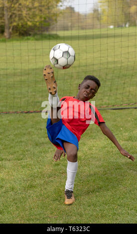 Hampshire, England, UK. April 2019. Ein junger Fußballspieler verteidigen das Ziel während eines Training Session in einem öffentlichen Park. Stockfoto