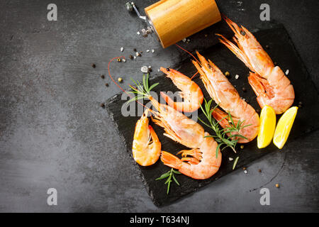 Fisch und Meeresfrüchte. Rohe Garnelen mit Spice und Zitrone auf einer Schiefertafel. Ansicht von oben flach Hintergrund. Freier Platz für Ihren Text. Stockfoto