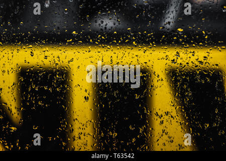 Regen fällt das Fenster mit unscharfen Schwarz-gelbe minimalen Hintergrund Stockfoto