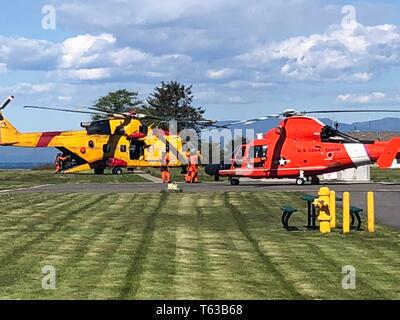 Einem MH-65 Dolphin helicopter aircrew von Coast Guard Sektor Field Office Port Angeles, Washington, Transfers zwei Patienten zu einem Royal Canadian helicopter Aircrew in Neah Bay, Washington, 28. April 2019. Die Küstenwache aircrew gerettet zwei bootsfahrer von einem Strand in der Nähe von Tsusiat Falls, British Columbia nach dem bootsfahrer Eine mayday Anruf getätigt haben. Foto mit freundlicher Genehmigung der US-Küstenwache Sektor Field Office Port Angeles. Stockfoto