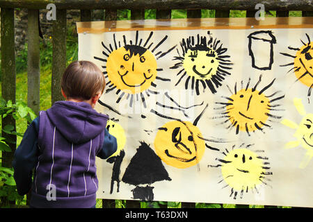 Babymädchen malt die Sonne auf der großen Papier im freien Stockfoto