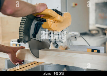 Arbeitnehmer Kürzungen einen Holzbalken Kreissäge. Moderne Ausstattung. Stockfoto