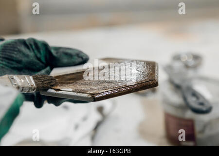 Arbeitnehmer malt eine Holz- Produkt in Braun. Nahaufnahme Stockfoto