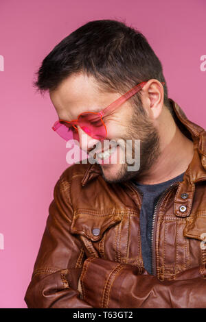 Foto auf der Seite des happy Brunet in rosa Brille und Lederjacke Stockfoto