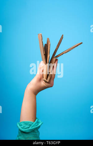 Hand mit Zerknüllten Karton auf blauem Hintergrund Stockfoto