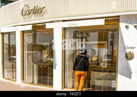 CANNES, Frankreich - April 2019: Person, die in das Fenster des Cartier Store auf der Strandpromenade von Cannes. Stockfoto