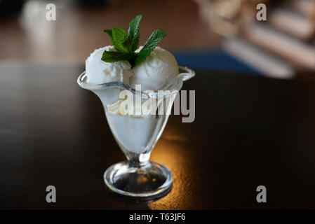 Kugeln mit Milch, Eiscreme in ein schönes Glas mit einem Zweig Minze in ein Restaurant Stockfoto