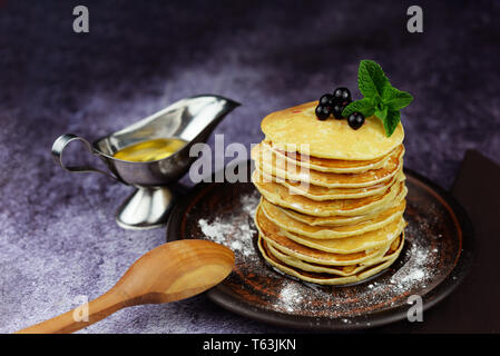 Amerikanische Pfannkuchen auf einen Teller mit Honig Johannisbeeren, Beeren und einem Blatt Minze Stockfoto