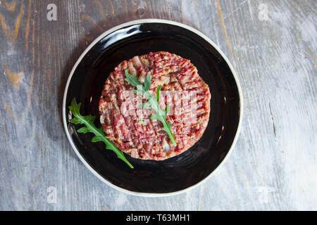 Steak Tartare, schneiden sie in Scheiben geschnitten und mit einem Messer, der Boden Hackfleisch, auf Anzeige auf einem rustikalen Holztisch. Steak Tartar ist ein symbolischer Gericht der F Stockfoto