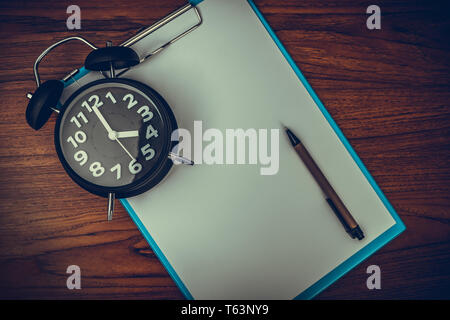 Schwarz Vintage Wecker mit Zwischenablage und leeres weißes Papier und Stift, kopieren Sie Platz für Ihren Text hinzufügen, Arbeit auf Zeit oder über Zeit und Termin konzept i Stockfoto