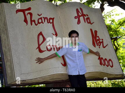 Ein Teenager posiert mit einer riesigen Buchskulptur, die den 1000th. Jahrestag der Gründung von Hanoi, Vietnam, in Hanoi, Vietnam feiert. Stockfoto