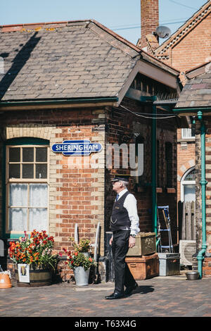 Sheringham, Großbritannien - 21 April, 2019: Leiter in Uniform zu Fuß auf einer Plattform von Sheringham retro Bahnhof. Sheringham ist eine englische Stadt am Meer w Stockfoto