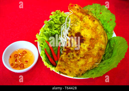 Banh xeo-vietnamesischen traditionellen Street Food gelb knusprigen Reis Mehl Kuchen mit Pilz Garnelen mung bean Sprout sizzling Kuchen mit Fisch sauce Chili Stockfoto