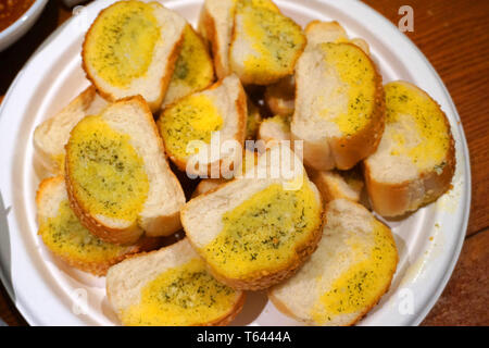 Lecker Knoblauch Brotscheiben mit Butter Käse Petersilie Frühlingszwiebel gesundes Frühstück auf weiße Platte geröstetes Baguette knuspriges Beilage Stockfoto