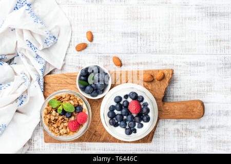 Joghurt mit Beeren und Müsli in den jar, Table Top Aussicht auf weißem Holz- Hintergrund. Kopieren Sie Platz für Text Stockfoto