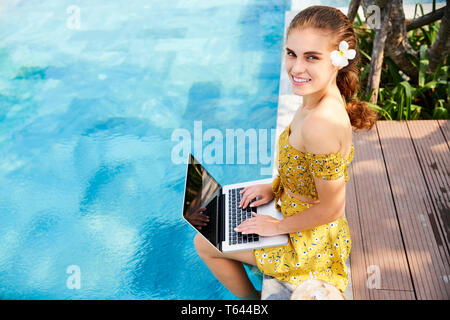 Frau sitzt am Pool Stockfoto