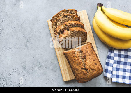 Banana Bread Loaf mit Mandeln Nüsse in Scheiben geschnitten auf grauem Beton Hintergrund. Table Top ansehen und kopieren Raum Stockfoto