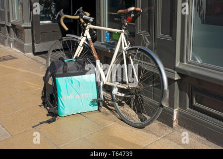 Nahaufnahme der Deliveroo box Essen Mahlzeit Lieferung Unternehmen Service und Fahrrad vor Restaurant England UK Vereinigtes Königreich GB Großbritannien geparkt Stockfoto