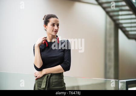 Ein Porträt der glückliche junge geschäftsfrau mit Kopfhörern im Korridor vor. Stockfoto