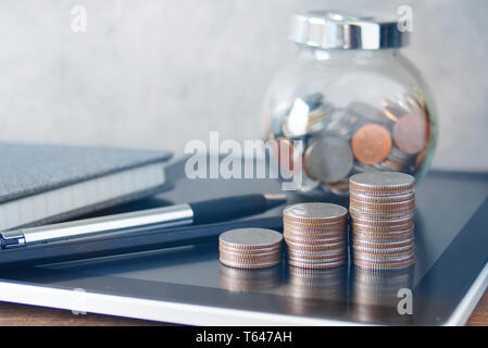 Wachstum Form Münzen stack und Stift und Glas Schale tragen Münzen auf Tablet auf den Tisch legen, das Finanzkonzept. Stockfoto