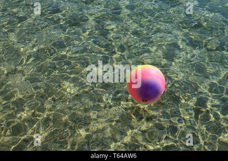 Strand Erholung Konzept, bunten beach ball schwimmt auf der Oberfläche von klaren, transparenten Meer Wasser, viel Platz funkelt, kopieren Stockfoto