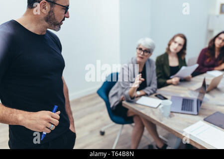 Unternehmer im Gespräch mit Kollegen während einer Sitzung im Büro. Reifen executive Hören auf Anregungen von seiner Mannschaft während einer Präsentation. Stockfoto