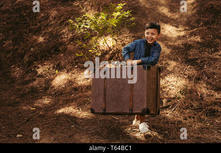 Junge auf einem Park weg mit alten Koffer in den Händen. Kind vorgibt, auf Ferien gehen werden. Stockfoto