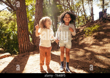 Lächelnde Mädchen Spaß im Wald. Kinder gemeinsam springen im Freien. Stockfoto