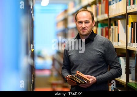Oldenburg, Deutschland. 11 Apr, 2019. Stefan Walter, wissenschaftlicher Mitarbeiter am Institut für Pädagogik an der Carl-von-Ossietzky-Universität Oldenburg, steht in einer Bibliothek mit ein paar Poesie Alben in seinen Händen. Walter hat recherchiert und seine Dissertation über Poesie Alben geschrieben. Credit: mohssen Assanimoghaddam/dpa/Alamy leben Nachrichten Stockfoto