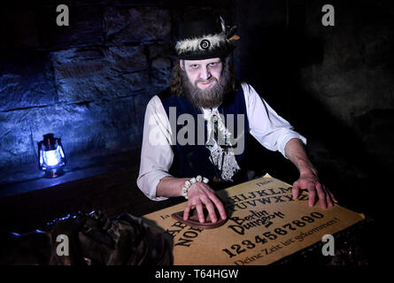 Berlin, Deutschland. 24 Apr, 2019. Der Schauspieler Alex van Ric (als Medium) mit einem Ouija Brett an der Berliner Dungeon. Die show éance - Haben Sie Ihr das Gefühl auch?" geht es um ein Medium, das versucht, den Geist einer Frau während einer Nekromantie zu zaubern. Quelle: Britta Pedersen/dpa-Zentralbild/ZB/dpa/Alamy leben Nachrichten Stockfoto