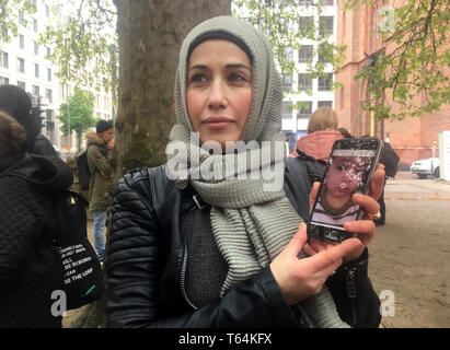 Berlin, Deutschland. 29 Apr, 2019. Intessar Aataba steht im Regen vor dem Auswärtigen Amt und zeigt das Foto von ihr Enkelkind auf Ihr Smartphone. Die Syrische Frau zeigt, gibt es für die Rückführung der Kinder ist Kämpfer aus Syrien. (Korr Bericht', wo man mit dem Deutschen Enkel des Kalifats?") Quelle: Ann Beatrice Clasmann/dpa/Alamy leben Nachrichten Stockfoto