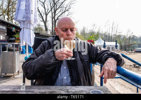 Berlin, Pankow. Weißensee Strandbad, älterer Mann trinkt ein Glas Weißwein im Cafe am Weißen See Badestrand Stockfoto