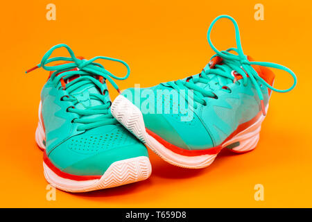 Rot, hellblau, weiß, Paar neue Tennisschuhe im Studio auf orangem Hintergrund isoliert. Stockfoto