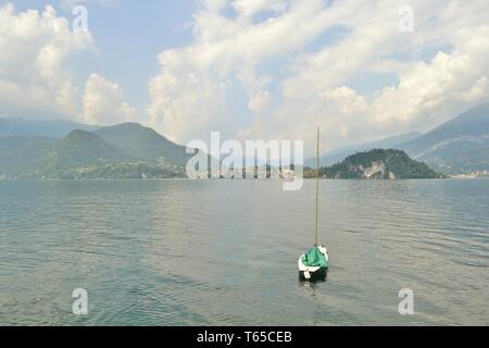 Schönen Panoramablick auf der Halbinsel Bellagio und den Comer See mit einem Segelboot im Wasser verankert, von Varenna am Seeufer in einer Feder sonnigen Tag. Stockfoto